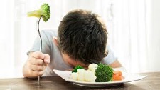 Young child with broccoli on his fork and head down