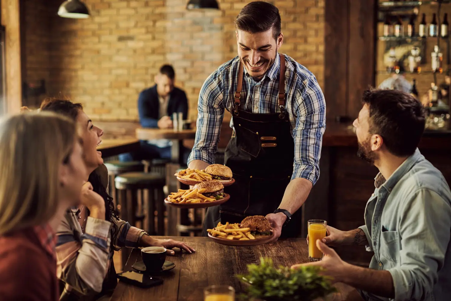 A waiter at a restaurant serving a group of people