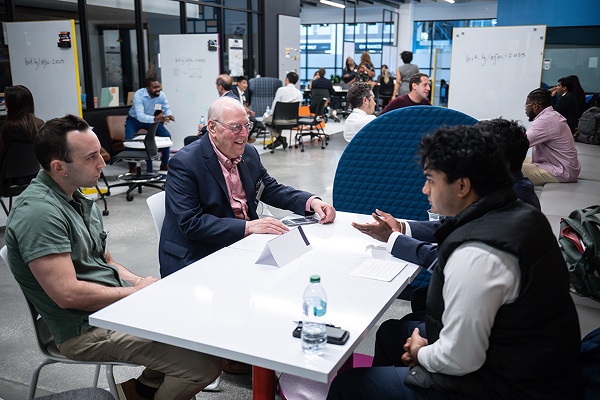students sitting at a table with their smiling mentor